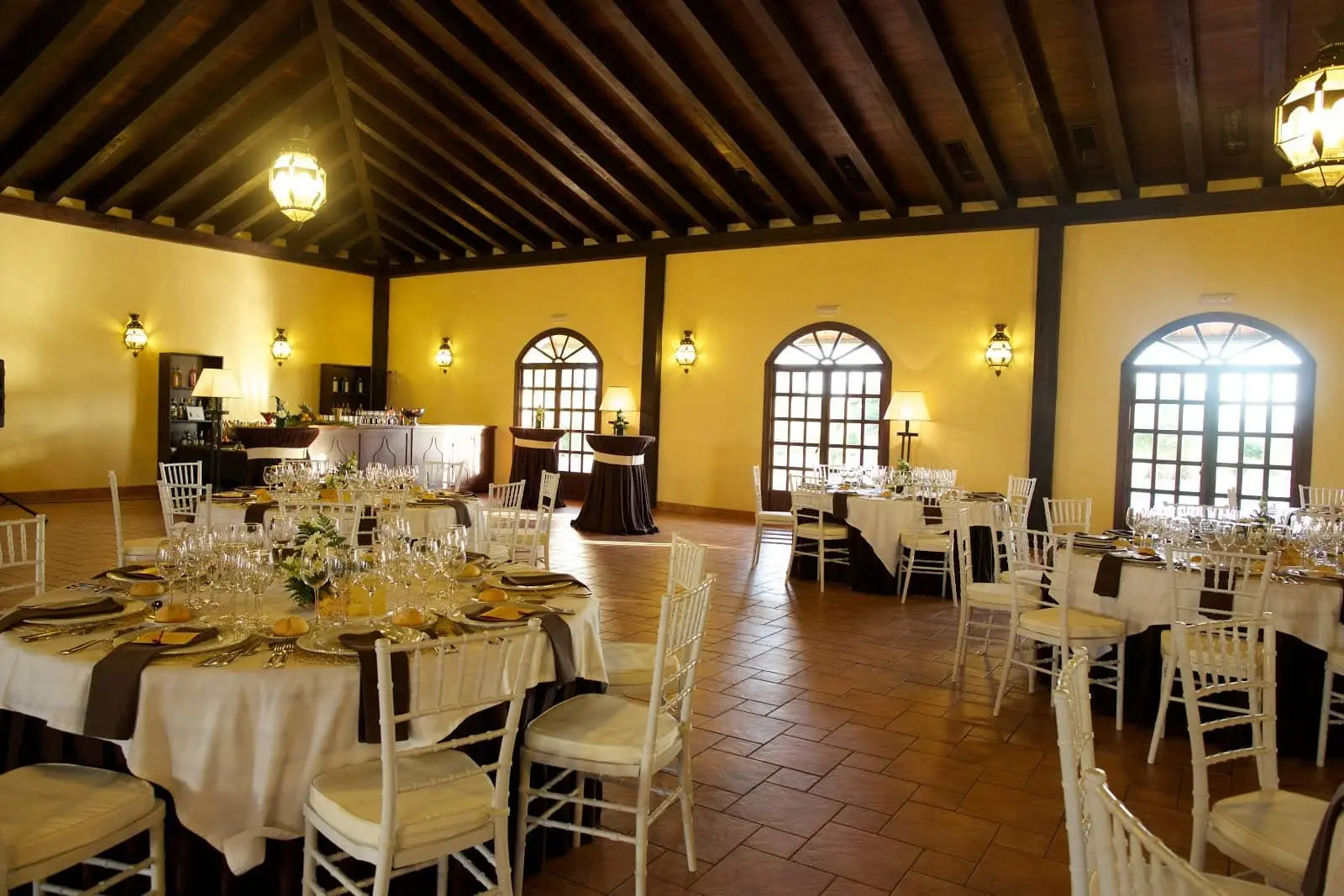 El salón principal, con su techo de madera y sus grandes ventanas, montado para un banquete