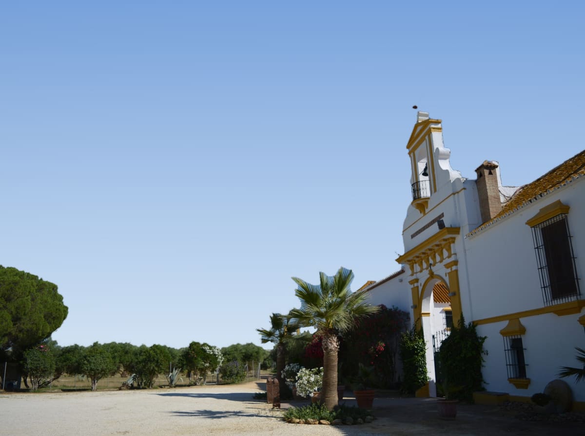 La fachada encalada de Hacienda Vera Cruz, con su espadaña y su arco de entrada, bajo un cielo azul despejado